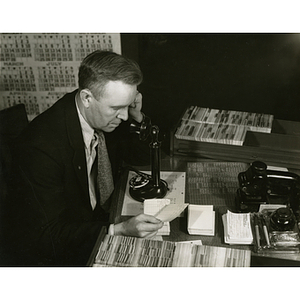 Business co-op student on telephone checking material for new Packard plant