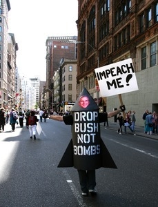 Protester dressed as a bomb with George Bush's head, opposing the war in Iraq, costume reads 'Drop Bush, not bombs' and 'Impeach me'
