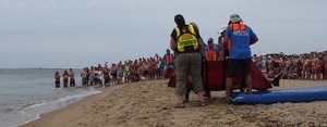 International Fund for Animal Welfare volunteers begin to lift dolphins off their mats to carry them to the water, with crowd looking on