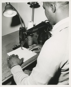 A man practices using a sewing machine at TOWER training