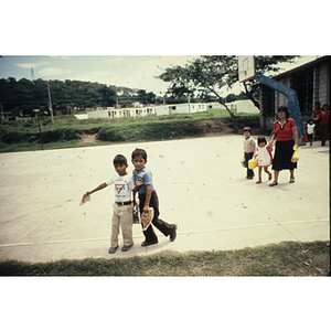 Two young boys pose on a basketball court