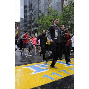 Wet "One Run" participants cross the Copley Square finish line