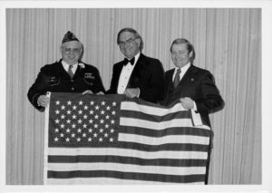 John Joseph Moakley, William M. Bulger, and a veteran holding an American flag at a veterans' event