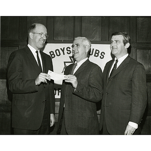 Charles H. Hood, at left, presents a check to an unidentified man and Frederick J. Davis, Executive Vice President of the Boys' Clubs of Boston