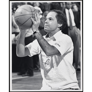 Boston television reporter [?] Peter Henderson holding a basketball and standing in shooting position at a fund-raising event held by the Boys and Girls Clubs of Boston and Boston Celtics