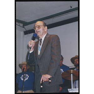 An elderly man speaks into a microphone at a Bunker Hillbilly alumni event