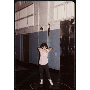 A girl stands in a circle putting on a t-shirt at the Charlestown gymnasium