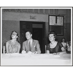 The panel of judges sits at a table, looking upwards during a Boys' Club Little Sister Contest