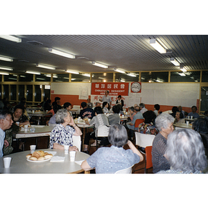 Man addresses people gathered for a Chinese Resident Association meeting