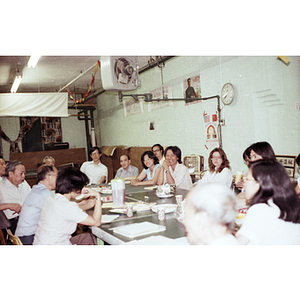 Chinese Progressive Association members sit around a table and converse during a tutoring class dinner