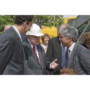 George J. Kostas speaks to two men at the groundbreaking of the George J. Kostas Research Institute for Homeland Security
