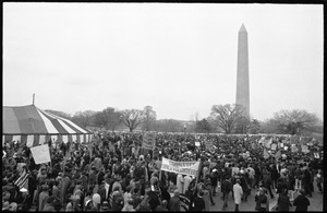 Giant tent pitched on the National Mall with Committee of Returned Volunteers (CRV) and other anti-war protesters milling about, the Washington Monument in the background: Counter-inaugural demonstrations, 1969
