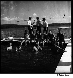 Camp Arcadia: camper with a guitar and swimmers on a floating dock