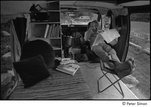 Ram Dass in his van: Ram Dass with his feet up, studying a map