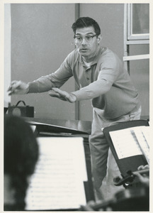 Joseph Contino, standing indoors conducting group of student musicians