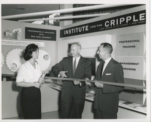 Two unidentified men cutting a ribbon next to an unidentified woman holding books in front of an ICD exhibit