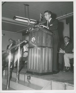 Unidentified man speaking behind podium at Institute Day