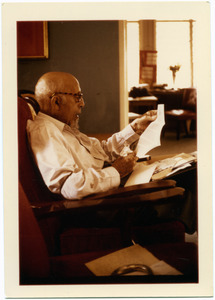 W. E.B . Du Bois, seated in a chair, reading