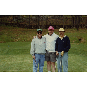 A three-man golf team posing on the golf course at a Boys and Girls Club Golf Tournament