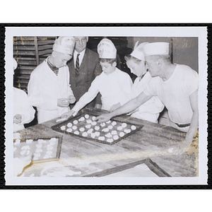 Members of the Tom Pappas Chefs' Club work with dough on sheet pans in a kitchen