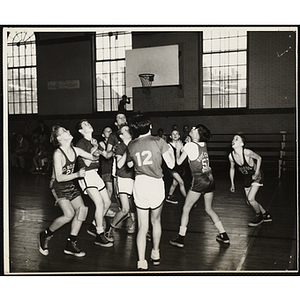 Players jockey for a ball in the air during a basketball game