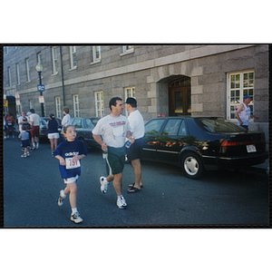 A girl and a man run in the Battle of Bunker Hill Road Race