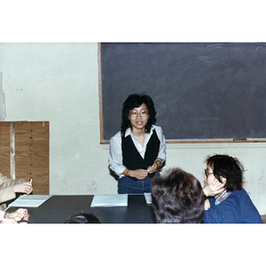 Teacher stands at the front of the classroom while her students listen