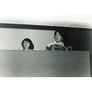 Man and woman adjust equipment in the Josiah Quincy School auditorium for an event regarding the normalization of U.S. and China relations