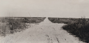 View of an empty road stretching through flat fields
