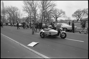 Motorcycle policeman in front of anti-Vietnam War marchers in the streets of Washington: Counter-inaugural demonstrations, 1969