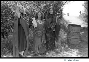 Drapeti, Cathy Brown (Usha), and Leenda standing by a waste barrel at Stinson Beach, raising their hands in a gesture