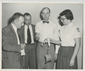 An occupational therapist and two men show a man a new prosthetic device