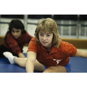 YMCA instructor stretching on gymnasium mat