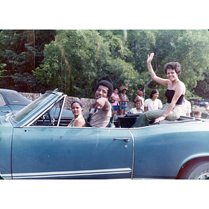 People sit in a blue convertible at the Festival Puertorriqueño