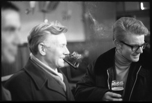 Man smoking a pipe and drinking with friends at the bar in a Scottish pub