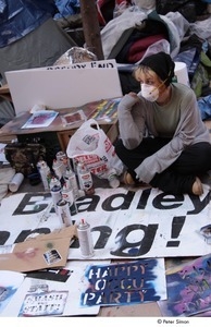 Occupy Wall Street: demonstrator wearing face mask and surrounded by spray paint and sign stencils