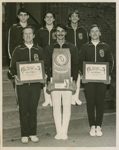 Springfield College Gymnasts and coach Wolcott with awards for 1976-1977 season, including NCAA Division II Championship Trophy