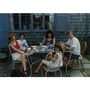 A man, two women, and two girls, seated around a table, smile for the camera during a Boys & Girls Club Board outing