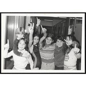 Six Boys and Girls Club members posing with their arms around each other, each of them holds up an index finger