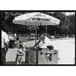 A teenage boy serves ice juice from a food cart to a girl on Boston Common