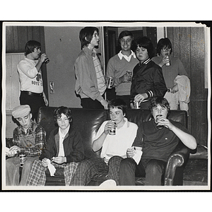 A group of teenage boys drink soda in a room