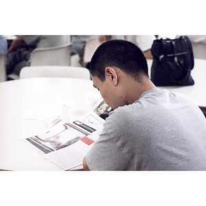 Young man reads a magazine during a Chinese Resident Association celebration