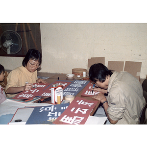 Man and a woman create Mel King campaign signs in Chinese before the August Moon Festival in Boston's Chinatown
