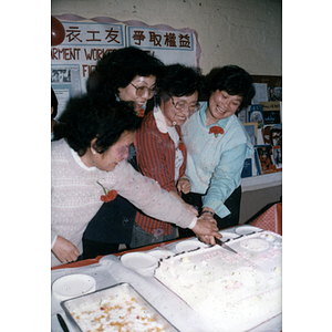 Four women cutting a cake