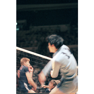 Chinese Men's Volleyball Team member plays in front of the net, while members of the United States men's team are visible behind the net