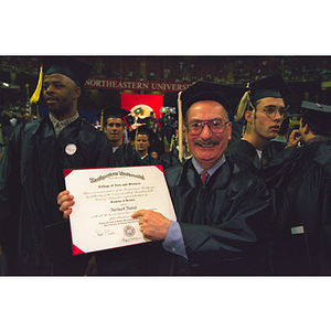 Herbert Hadad holding his diploma at commencement