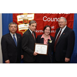 A woman poses with her certificate and three men at the National Council Dinner