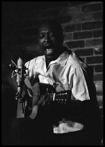 Josh White performing on guitar in a coffeehouse