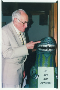 Sidney Lipshires (left) and inflatable dinosaur at his eightieth birthday party: '80 and not extinct'