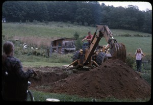 Backhoe digging the foundation for the greenhouse as Peter Natti and Janice Frey look on, Montague Farm Commune